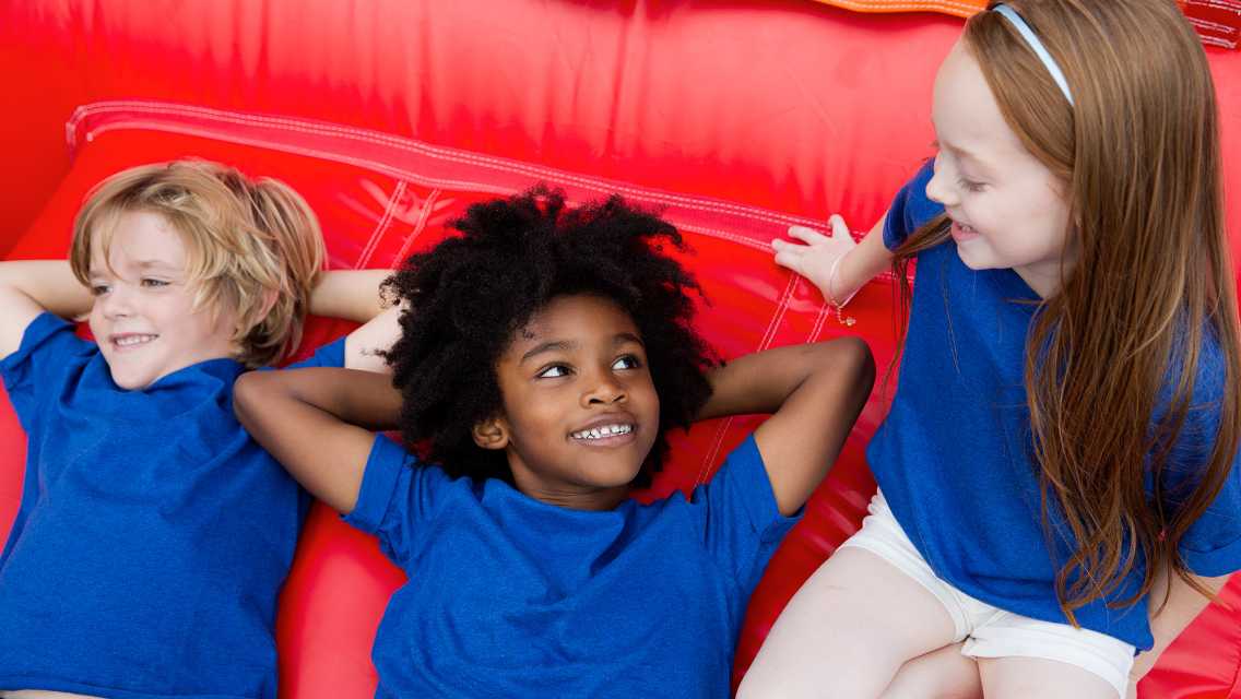 three kids laying in a bounce house