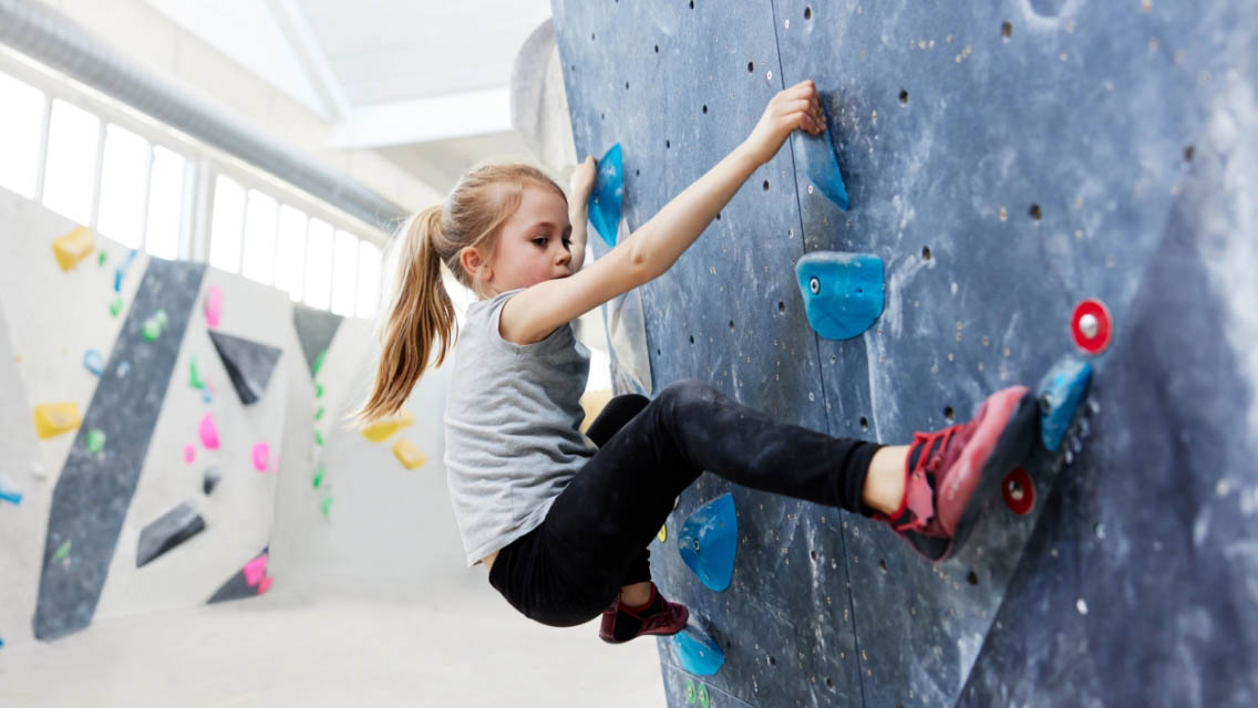a young girl climbing a rock wall