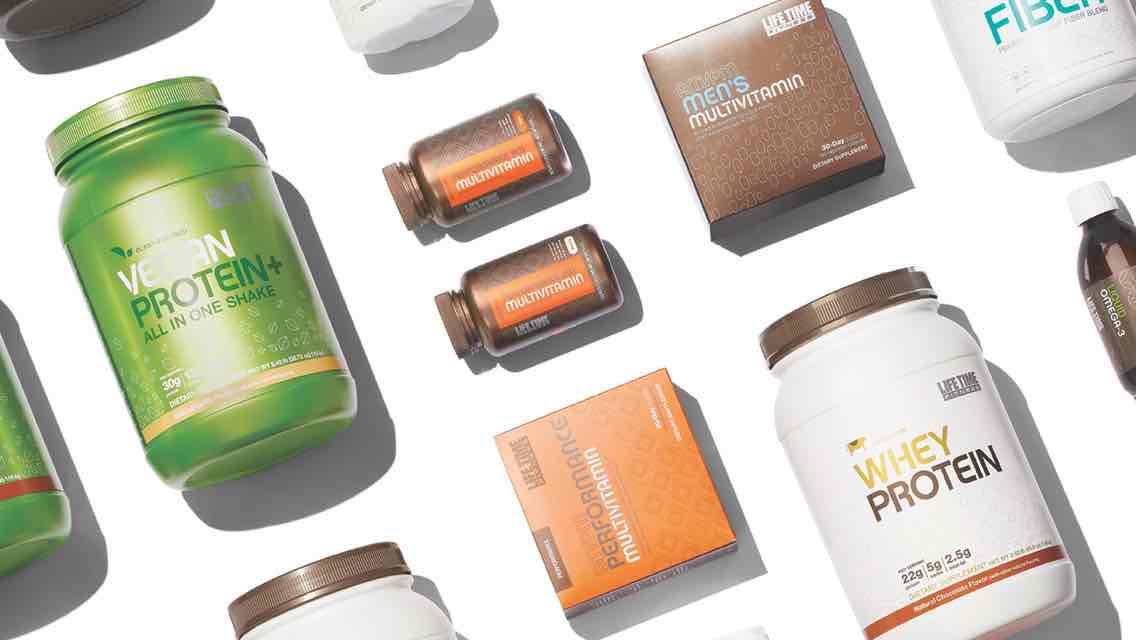 An array of Life Time supplements including containers of protein powder and bottles of multivitamins