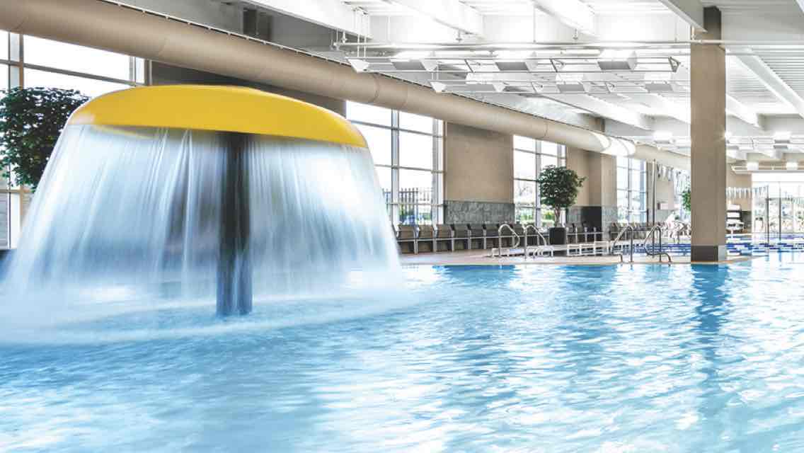 A brightly lit indoor pool featuring a yellow mushroom fountain with flowing water