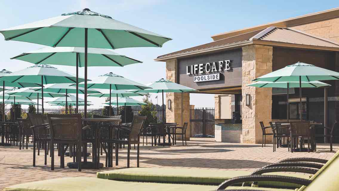 An outdoor Life Time LifeCafe surrounded by umbrella-covered outdoor tables and chairs