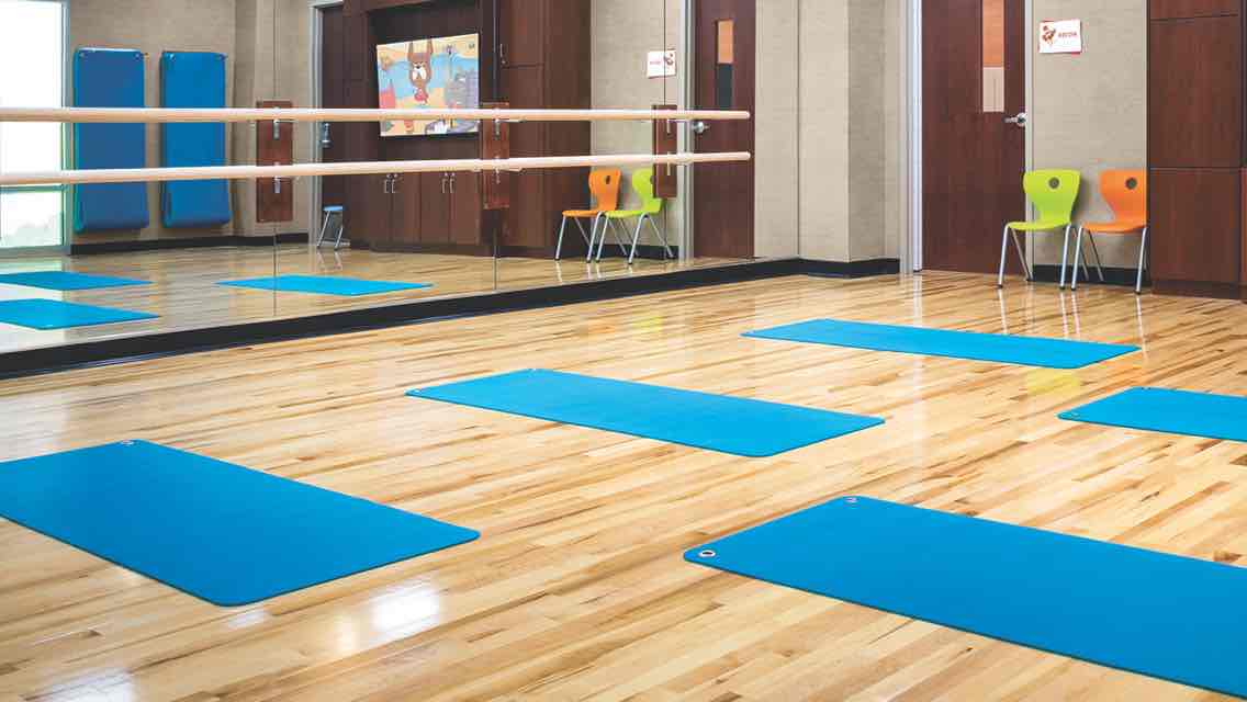 Five blue yoga lined up on the wood floor of a light-filled studio