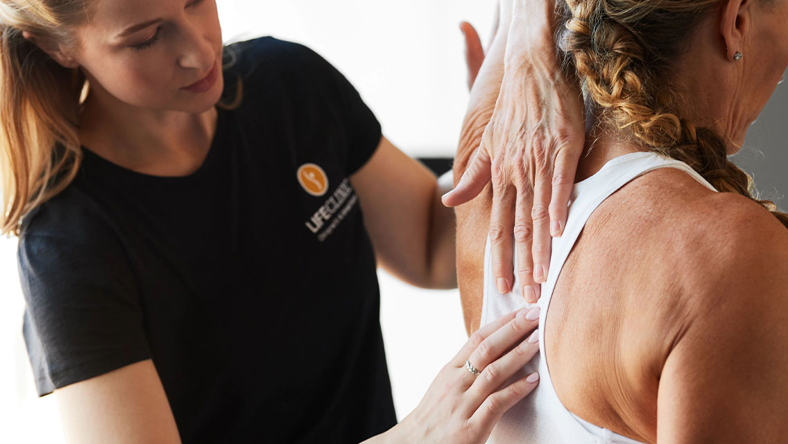 A physical therapist  touching the shoulder blade with a client
